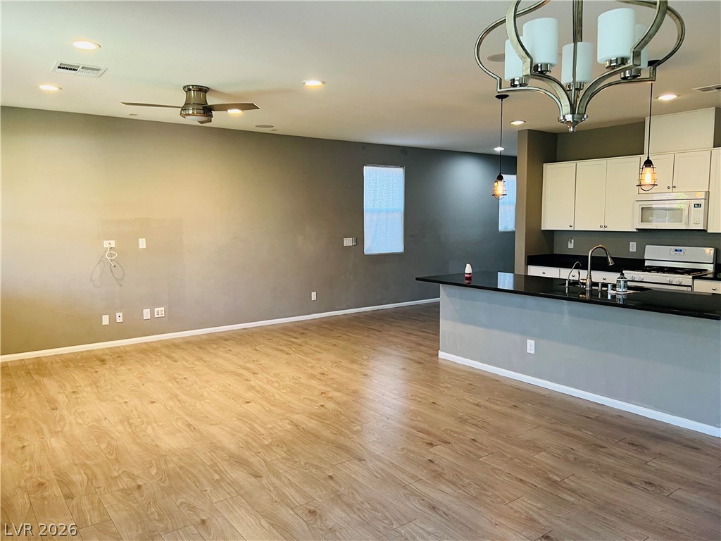 9325 Keystone Ridge Avenue Las Vegas, NV 89148 - Photo 5 of 17 An open-concept living space with rich wood flooring flows seamlessly into a modern kitchen, anchored by a sleek island.