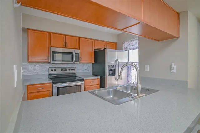 a kitchen with stainless steel appliances granite countertop a sink a stove top oven and a refrigerator