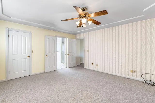an empty room with chandelier fan and windows
