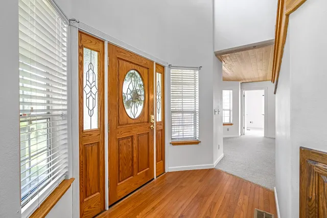 a kitchen with stainless steel appliances granite countertop a stove a sink dishwasher and white cabinets with wooden floor