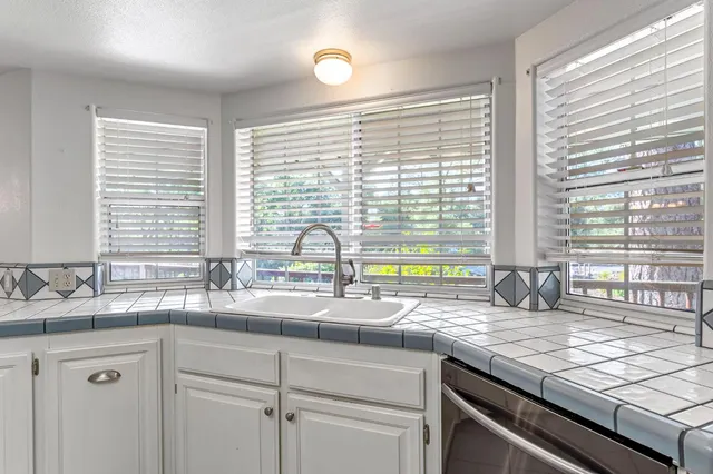 a large white kitchen with a large window cabinets and stainless steel appliances