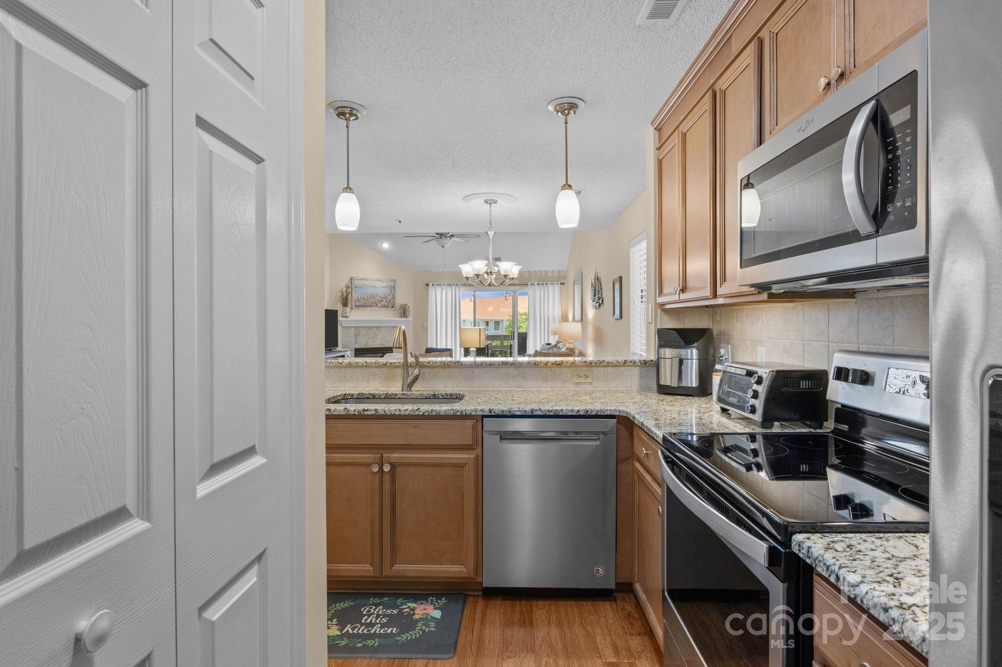 18009 Kings Point Drive, Unit I Cornelius, NC 28031 - Photo 11 of 47 a kitchen with stainless steel appliances granite countertop a sink a stove a microwave and cabinets