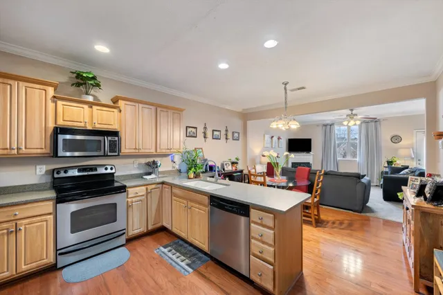 a kitchen with stainless steel appliances granite countertop a sink dishwasher stove and cabinets with wooden floor