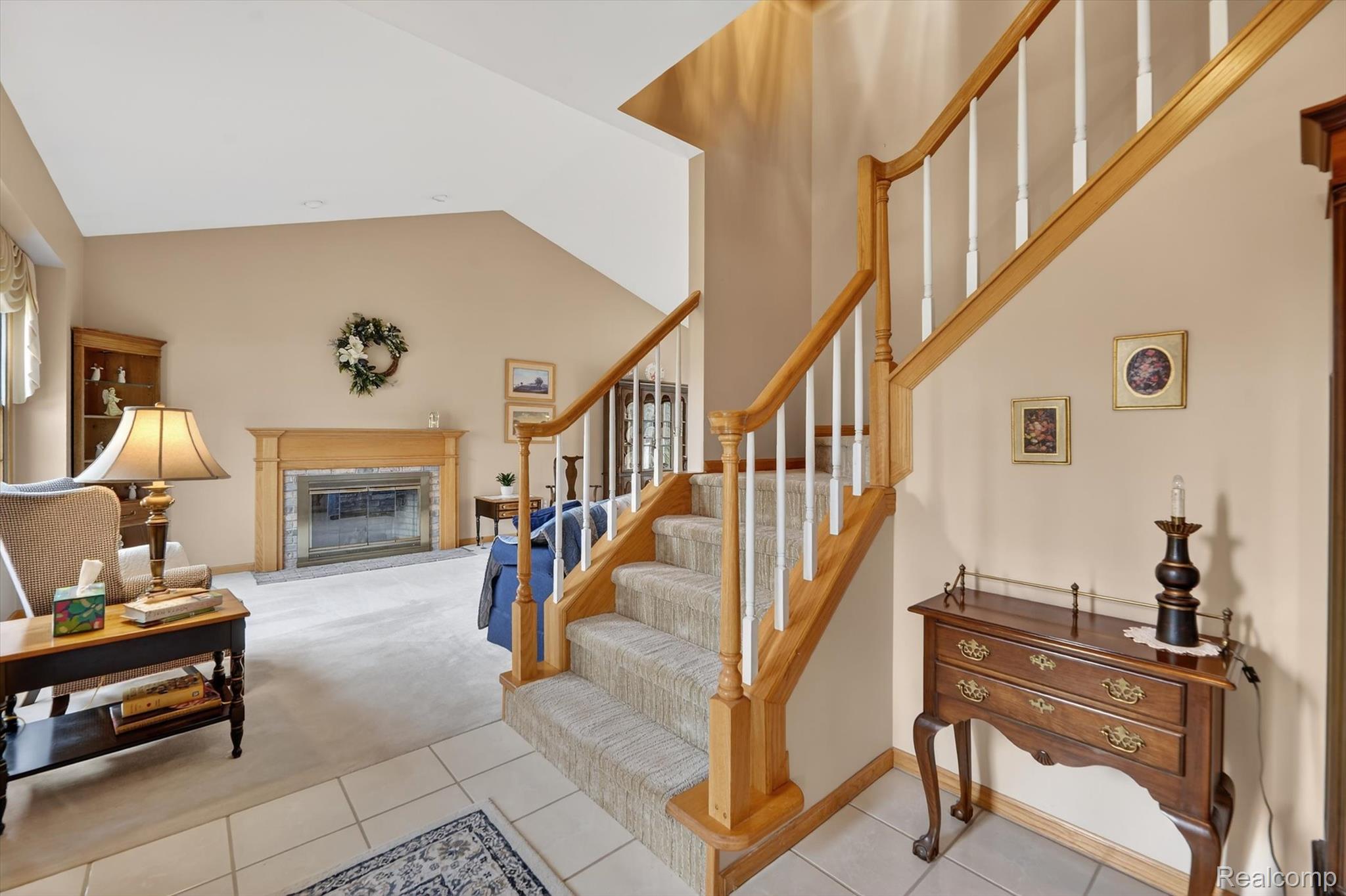 7798 Lee Road Brighton, MI 48116 - Photo 4 of 49 Staircase featuring carpet flooring, a glass covered fireplace, tile patterned floors, and a high ceiling