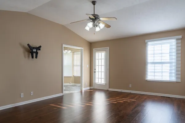 a view of an empty room with a window and wooden floor