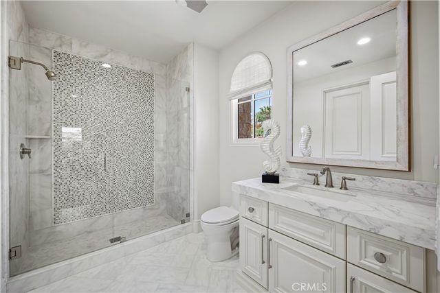 a bathroom with a granite countertop sink a toilet a mirror and shower