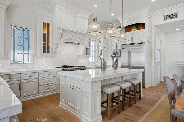 a kitchen with stainless steel appliances kitchen island granite countertop a table chairs sink and cabinets