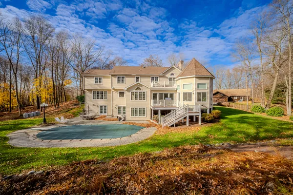 a view of a white house next to a yard with big trees
