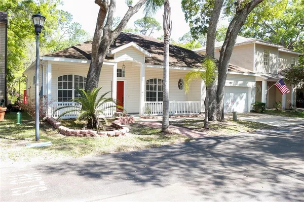 a view of a white house with a large tree and wooden fence