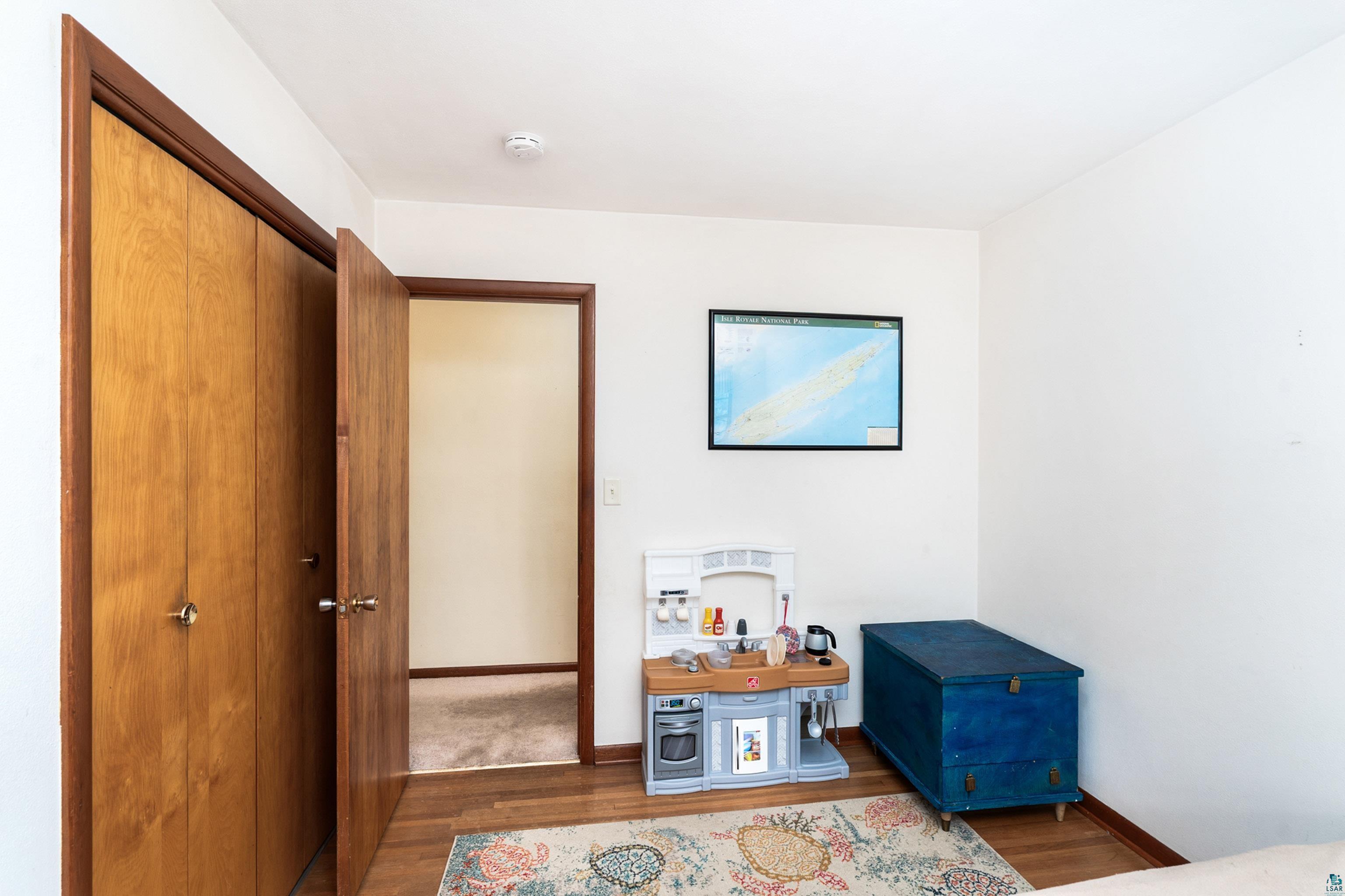 4808 Midway Road Duluth, MN 55811 - Photo 25 of 57 Room featuring wood-finish flooring, light-toned walls, and a wood bi-fold closet with brass hardware