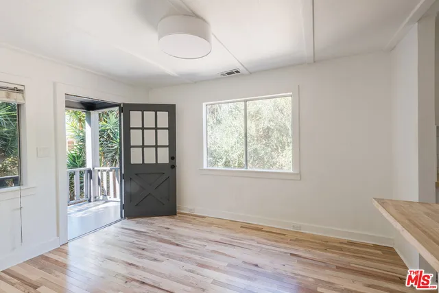 a view of an empty room with a window and wooden floor