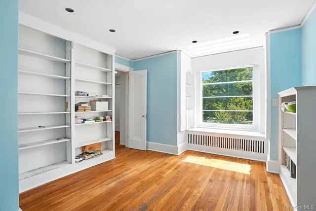 a view of an empty room with a window and wooden floor
