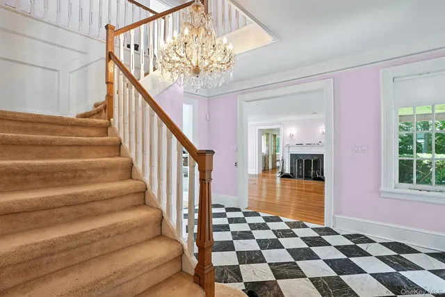 a view of a hallway with a black white checkered floor and chandelier
