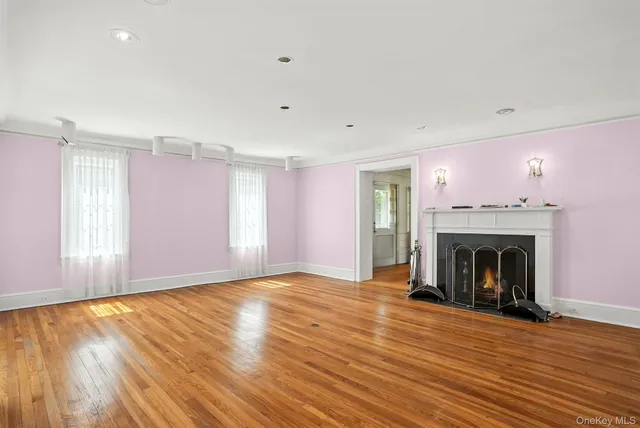 an empty room with wooden floor fireplace and windows
