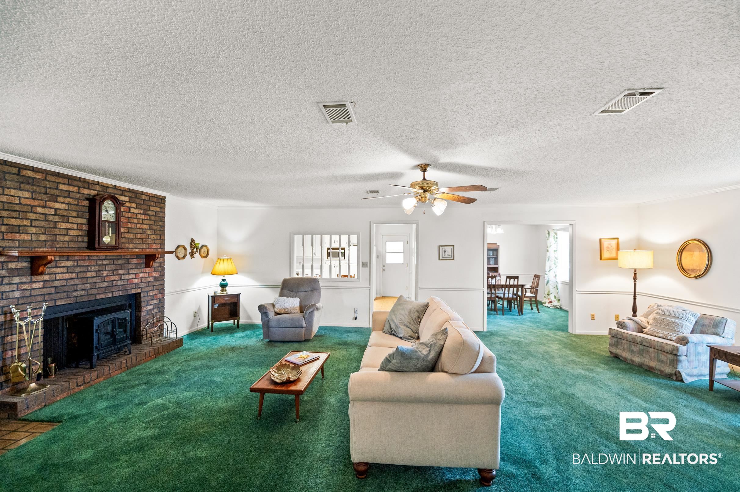 15600 Fackler Road Loxley, AL 36551 - Photo 7 of 51 Carpeted living room featuring a textured ceiling, plenty of natural light, ceiling fan, and a brick fireplace