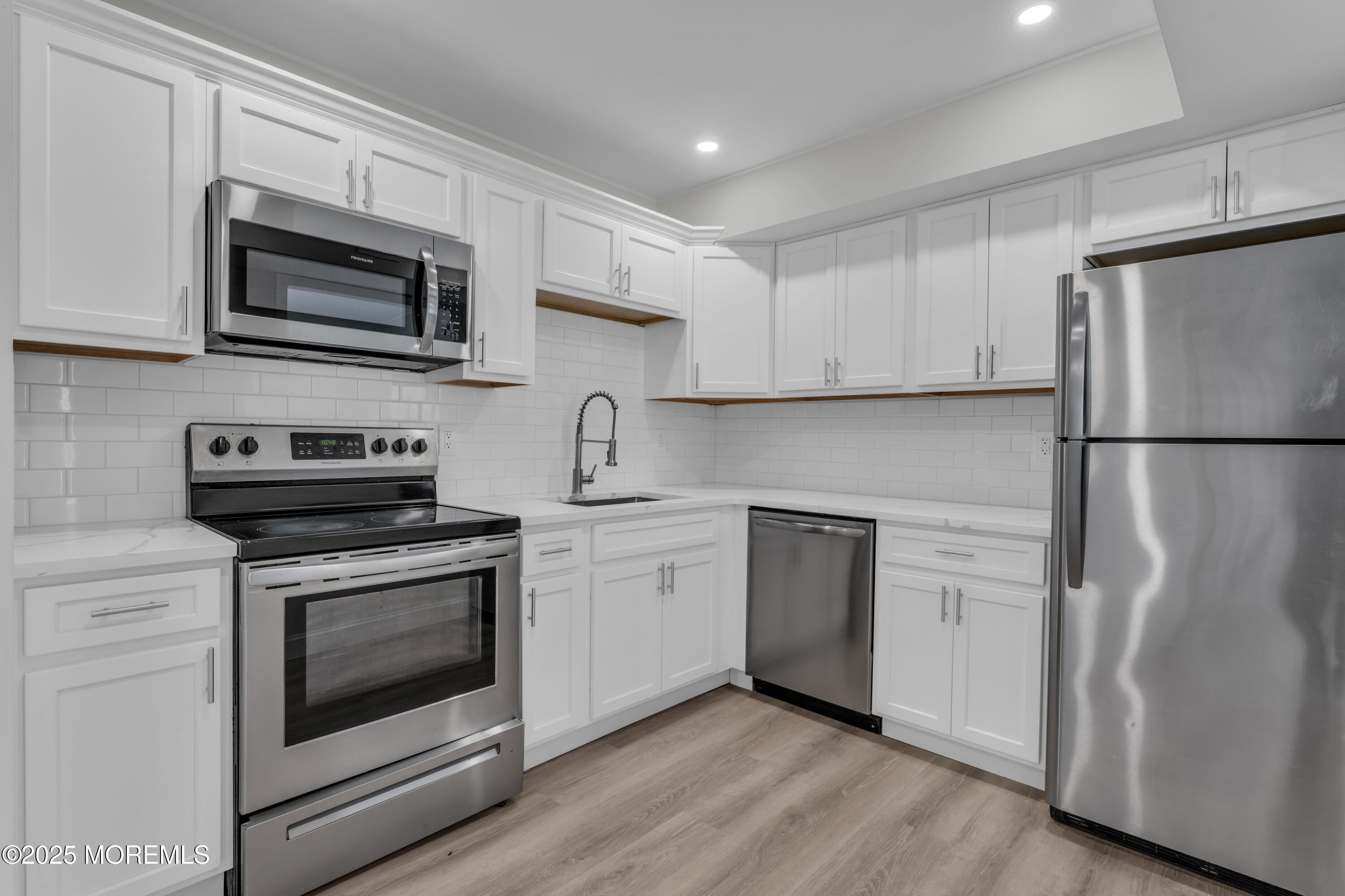 182 Greenwood Loop Road Brick, NJ 08724 - Photo 4 of 19 a kitchen with stainless steel appliances white cabinets white stove a microwave and a refrigerator