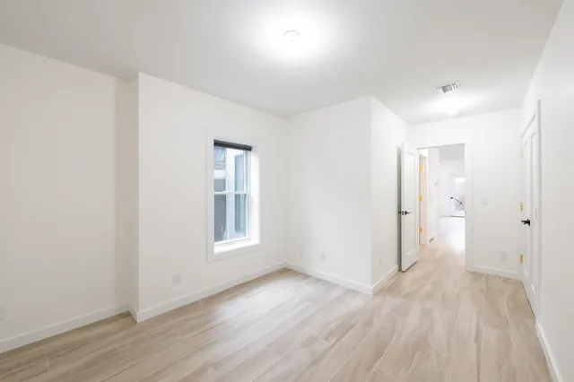 an empty room with wooden floor and windows