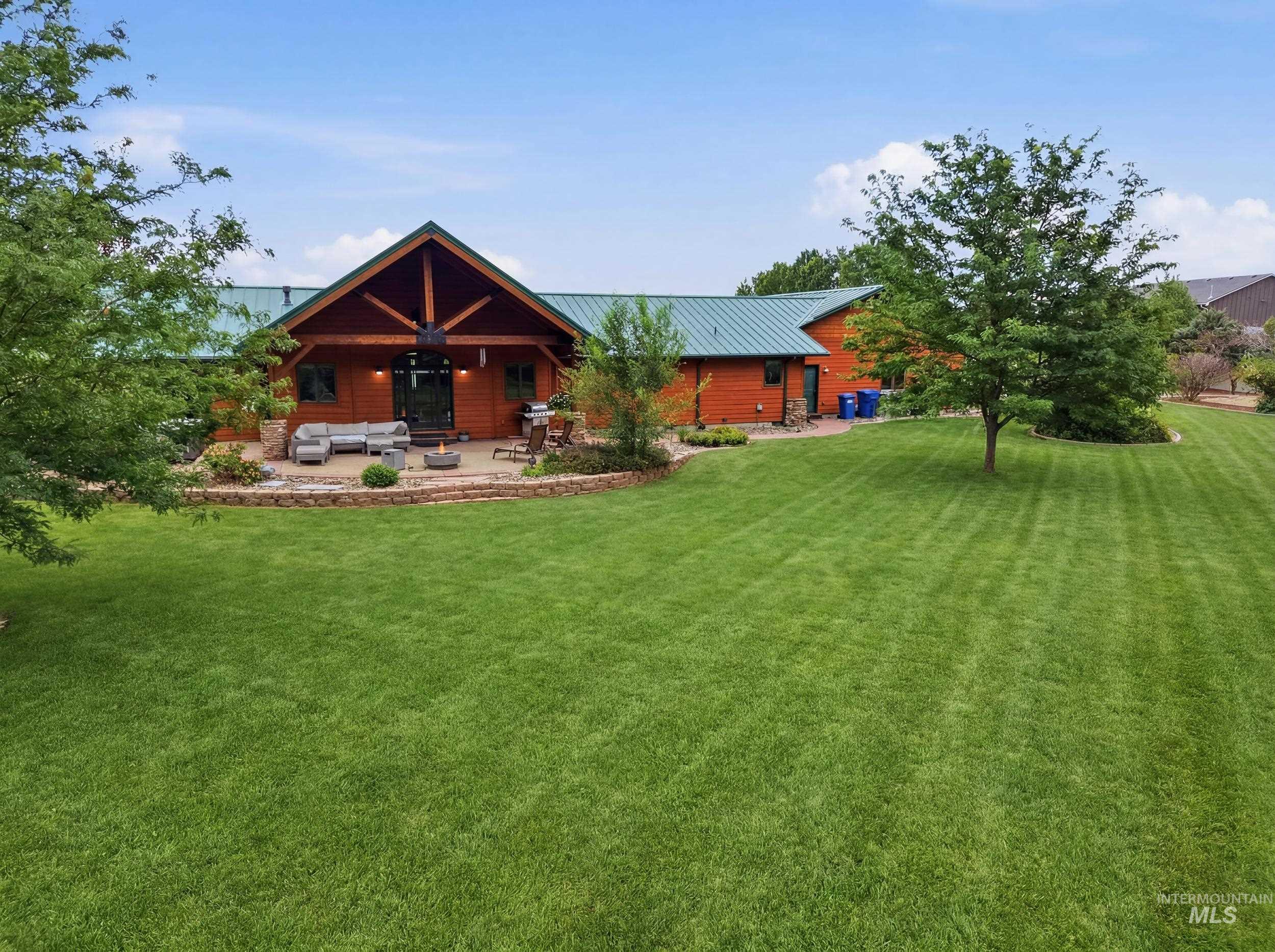 339 Airport Road Weiser, ID 83672 - Photo 45 of 49 Expansive green lawn with mature trees and a stone-bordered patio