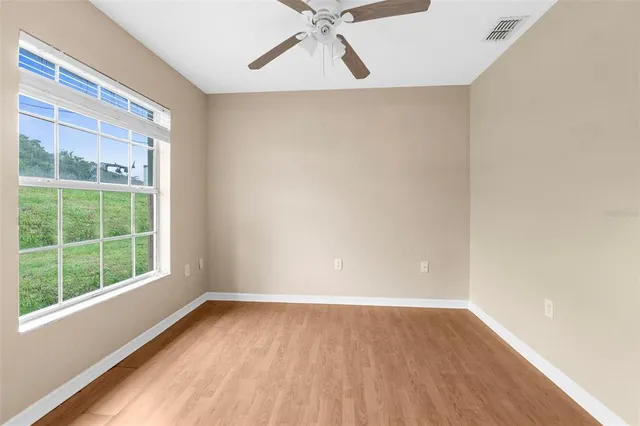 a view of an empty room with a window and wooden floor