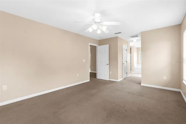a view of an empty room with a chandelier fan