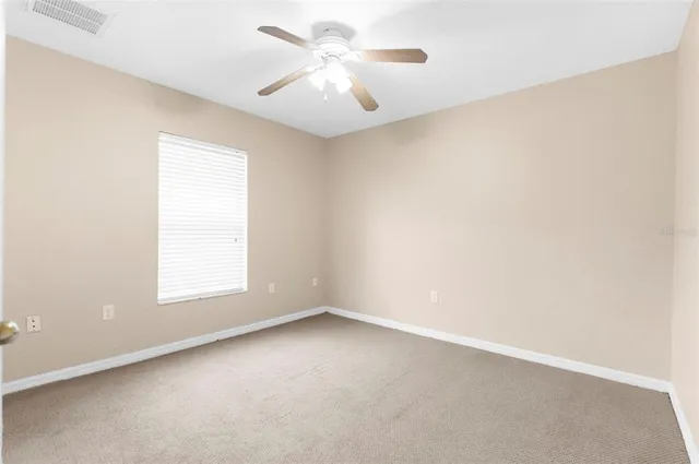 an empty room with a window and a ceiling fan