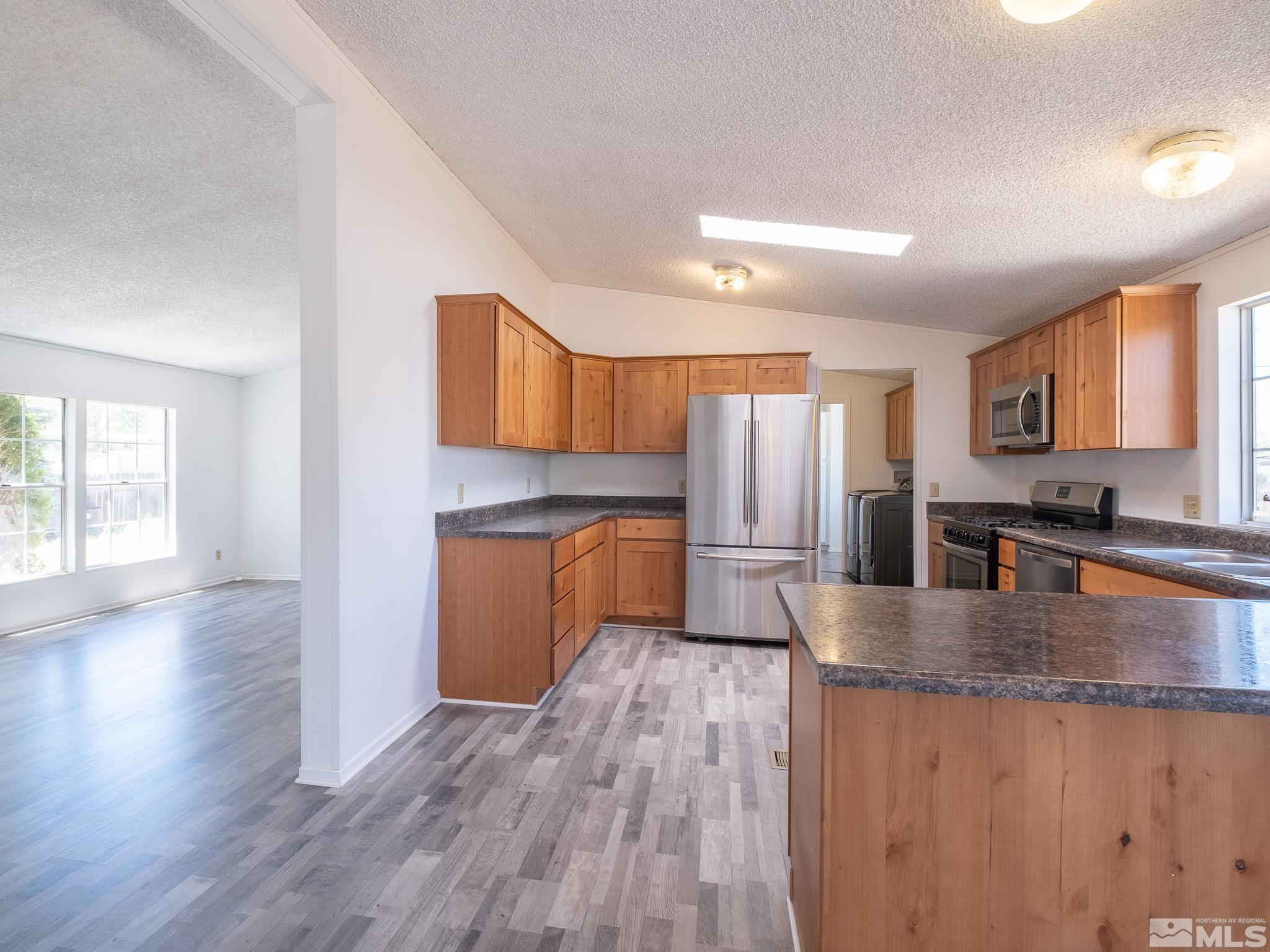 3975 Sandpiper Drive Reno, NV 89508 - Photo 13 of 35 a kitchen with granite countertop a stove top oven a sink dishwasher a refrigerator and cabinets with wooden floor