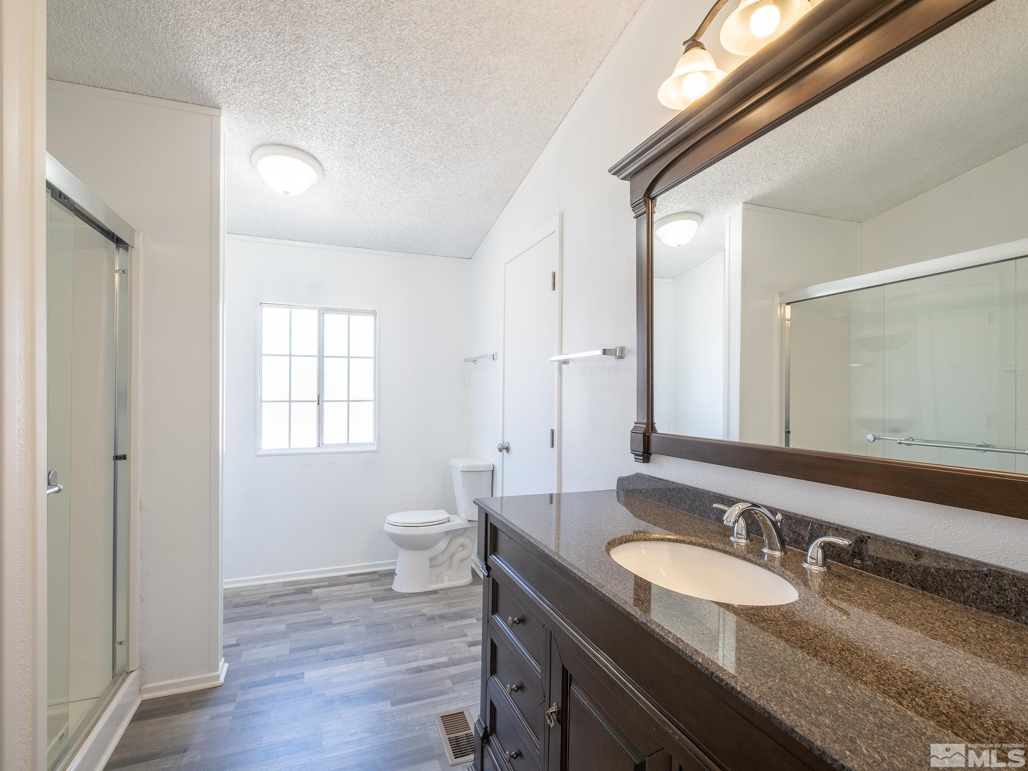 3975 Sandpiper Drive Reno, NV 89508 - Photo 10 of 35 a bathroom with a granite countertop double vanity sink a mirror and a toilet