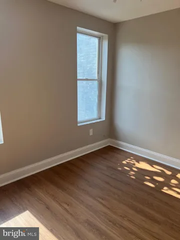 a view of an empty room with wooden floor and closet