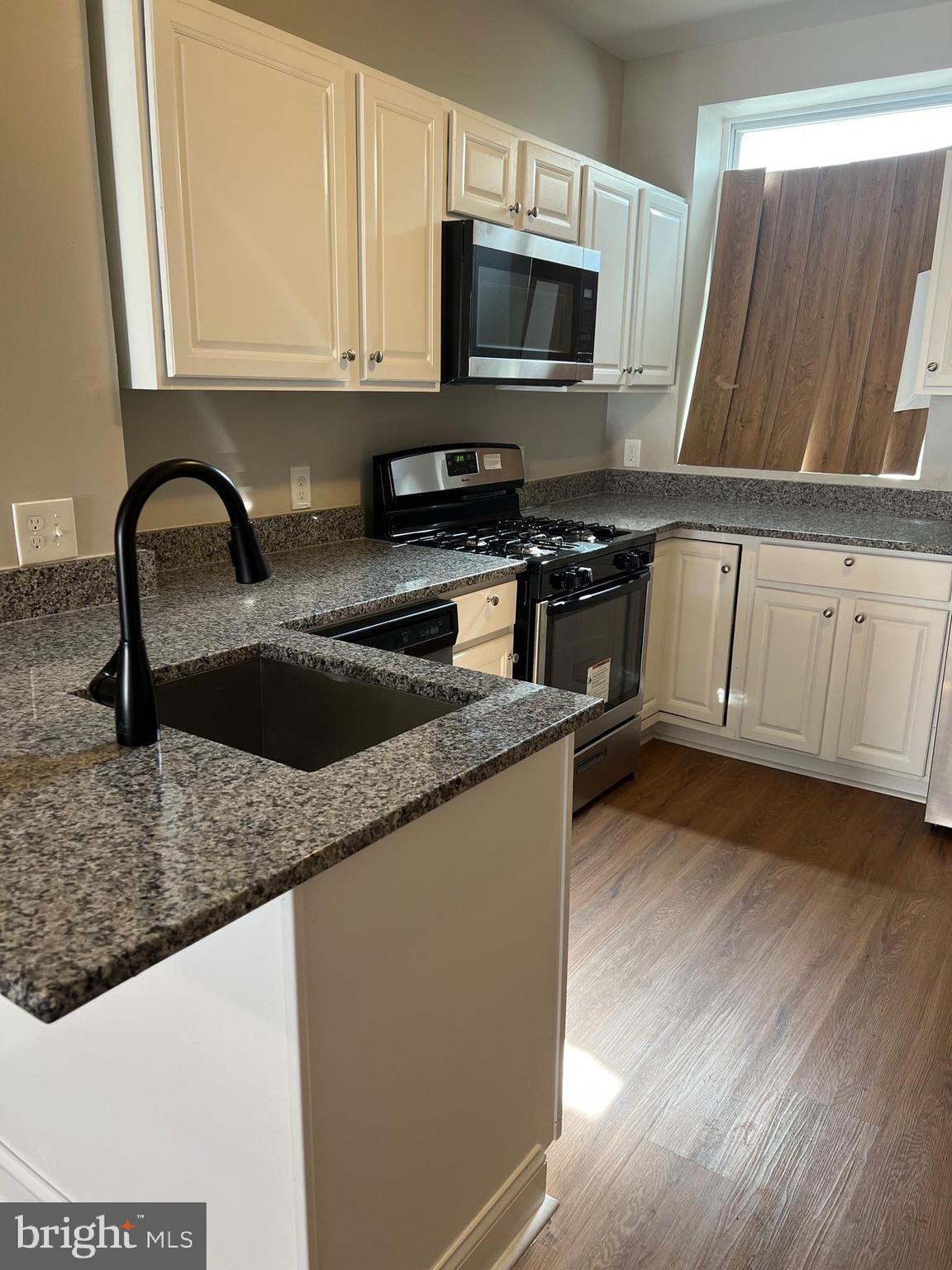 820 North Rose Street Baltimore, MD 21205 - Photo 5 of 20 a kitchen with granite countertop a sink a microwave and cabinets