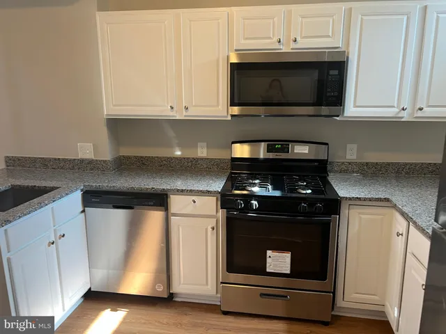 a kitchen with granite countertop white cabinets and stainless steel appliances