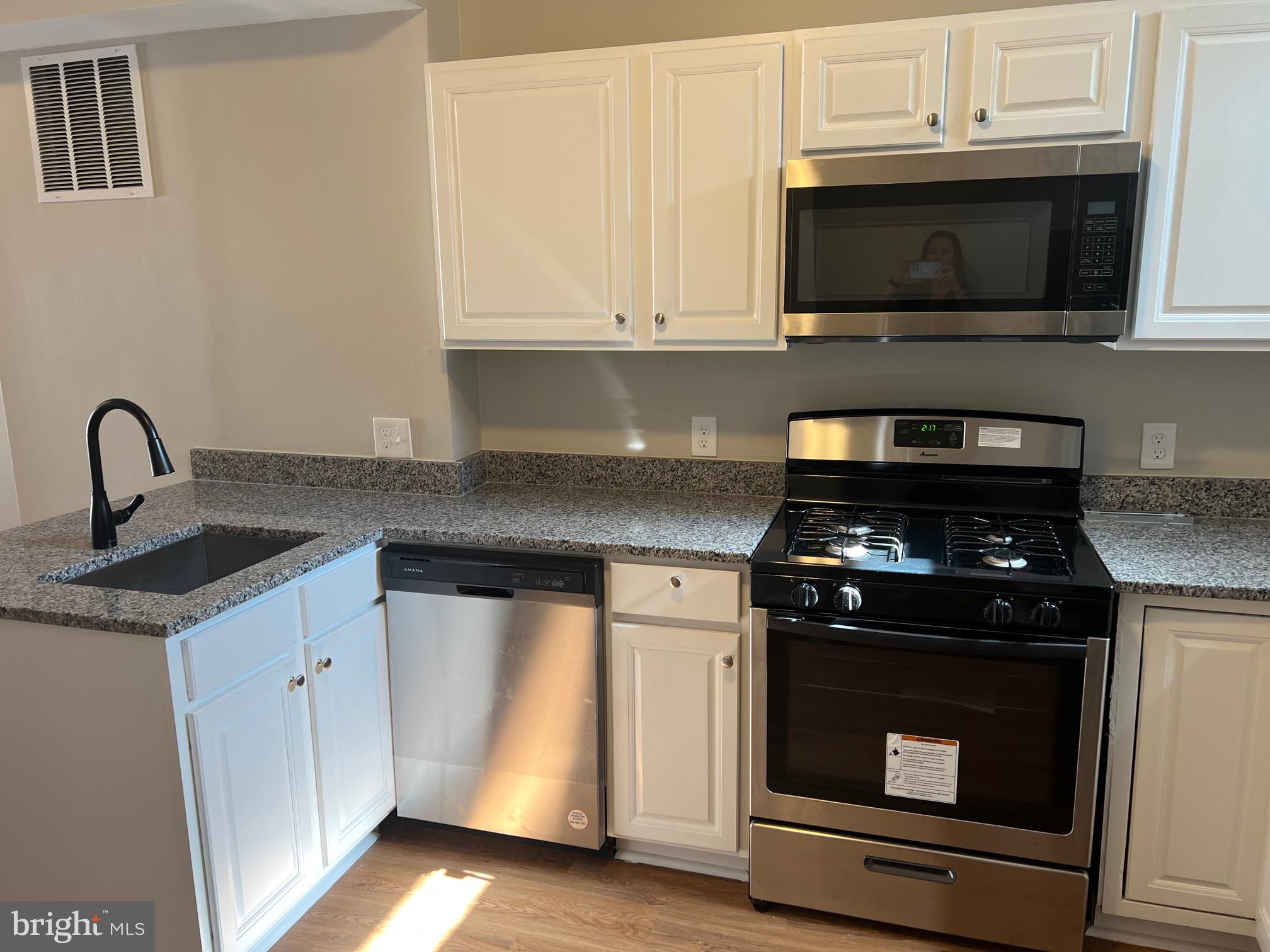 820 North Rose Street Baltimore, MD 21205 - Photo 7 of 20 a kitchen with granite countertop white cabinets and stainless steel appliances