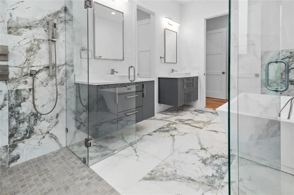 309 Kaye Street Coppell, TX 75019 - Photo 21 of 36 Modern bathroom featuring a glass-enclosed shower with a mosaic tile floor, a freestanding soaking tub, and a dual vanity with grey cabinetry