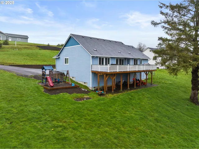 a view of a house with a big yard and large tree