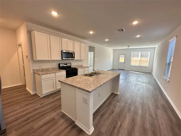 a kitchen with a sink wooden floor and stainless steel appliances