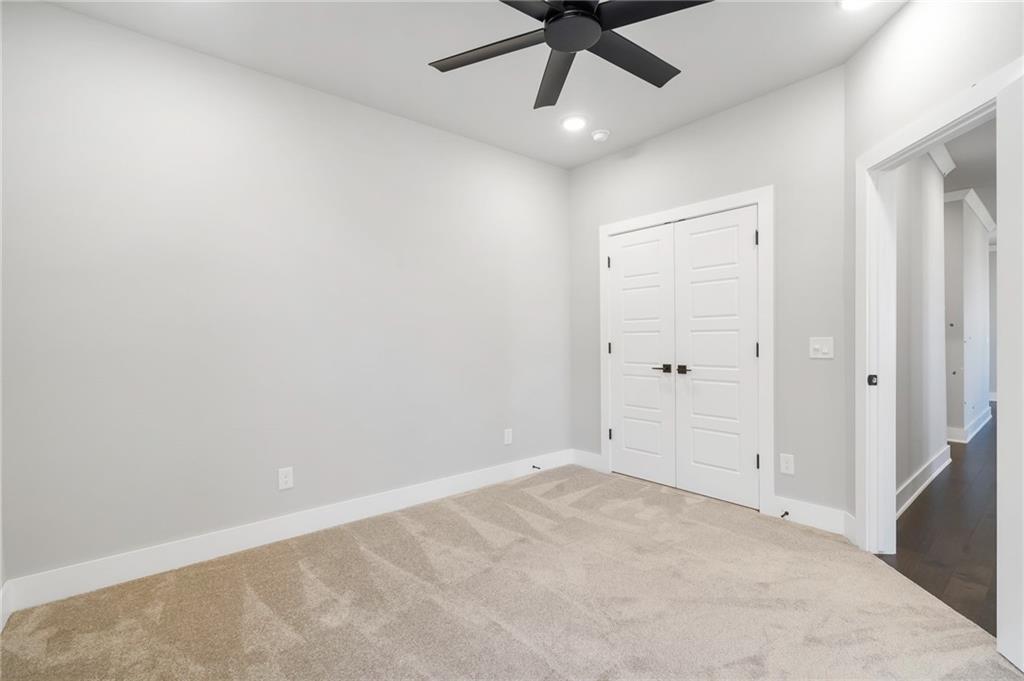 1910 Peacock Road Centerton, AR 72719 - Photo 22 of 29 Recessed lighting, ceiling fan, white paneled doors with black hardware, and neutral carpet flooring