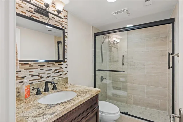 a bathroom with a granite countertop sink toilet a mirror and shower