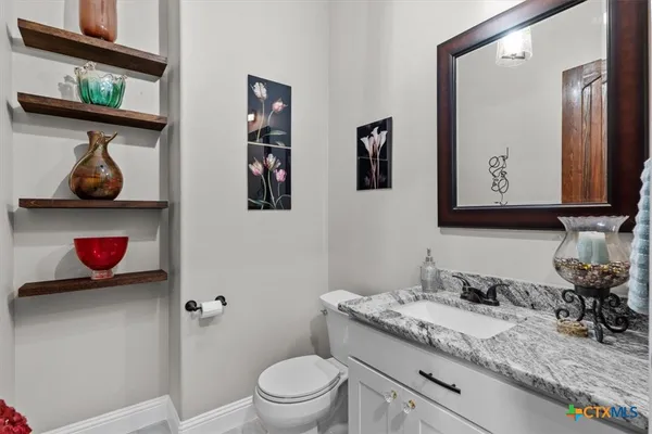 a bathroom with a granite countertop sink a toilet and a mirror