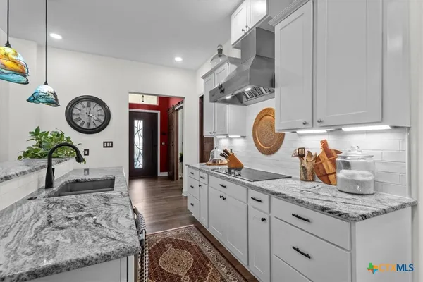 a living room with granite countertop a sink a stove top oven and clock on the wall