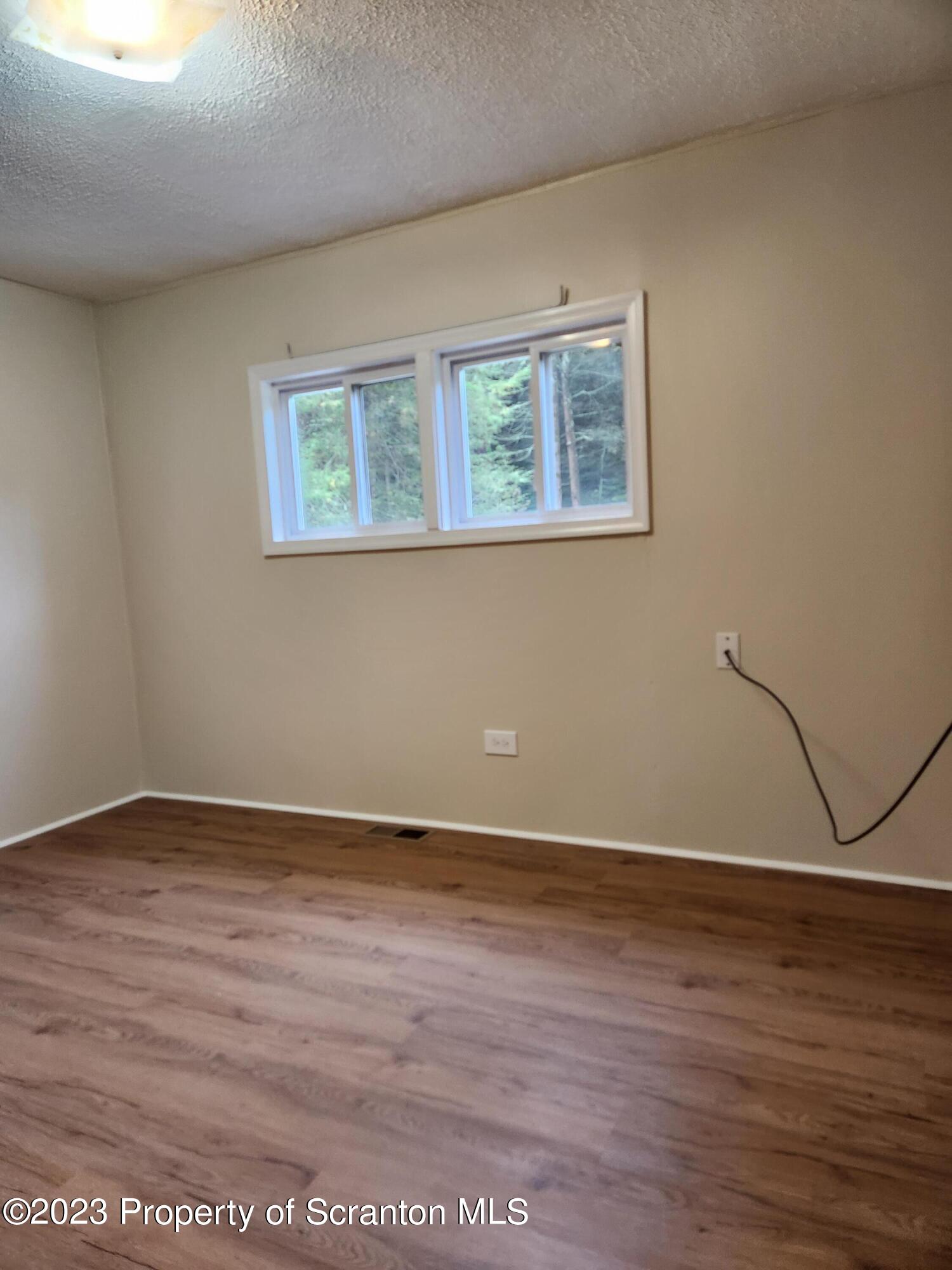 15325 Strickland Hill Road Springville, PA 18844 - Photo 16 of 20 a view of an empty room with wooden floor and a window