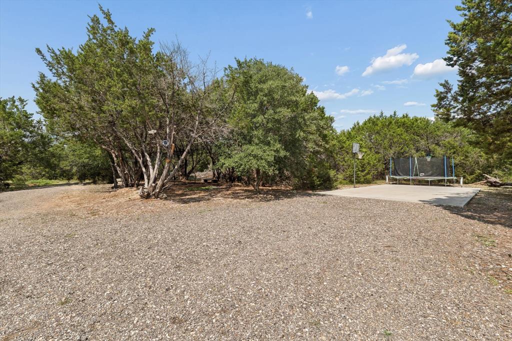 286 Benevolence Way China Spring, TX 76633 - Photo 35 of 37 Expansive gravel area leading to a concrete pad, surrounded by mature trees