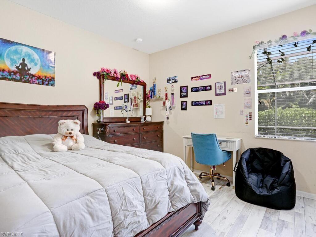 8143 Monticello Court Naples, FL 34104 - Photo 15 of 26 a bedroom with a bed and wooden floor