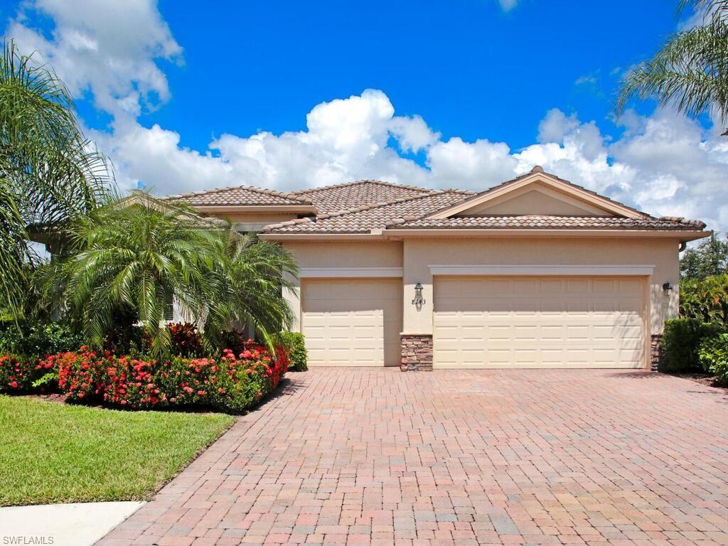 8143 Monticello Court Naples, FL 34104 - Photo 2 of 26 a front view of a house with a garden and yard