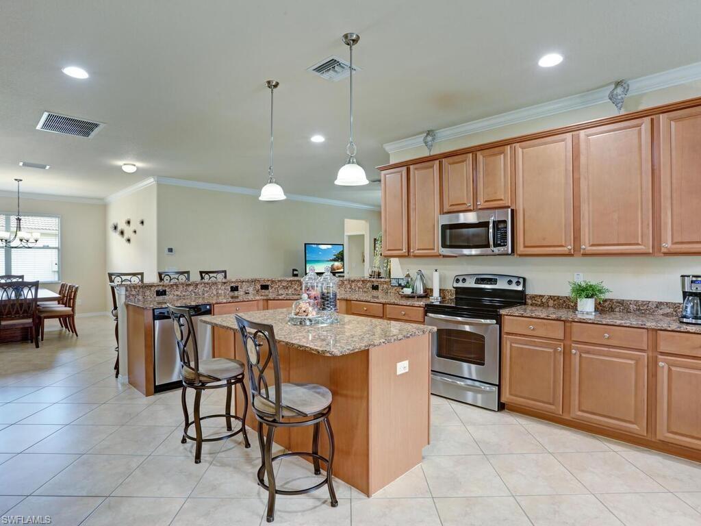 8143 Monticello Court Naples, FL 34104 - Photo 5 of 26 a kitchen with kitchen island granite countertop a sink a counter top space appliances and cabinets