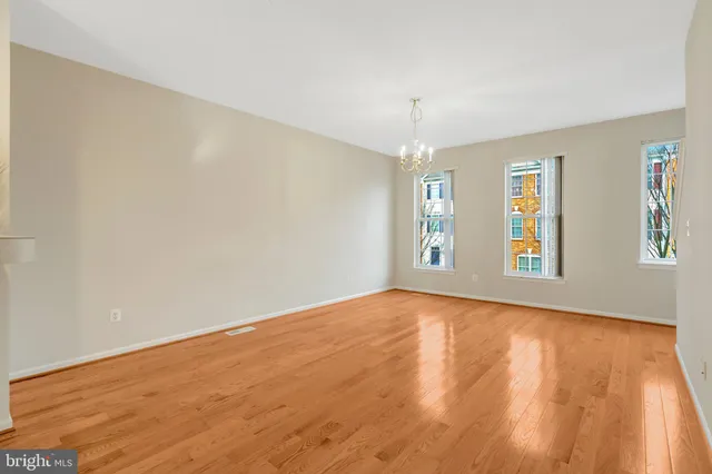 a view of an empty room with window and wooden floor