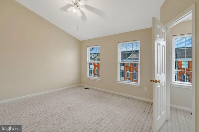 an empty room with windows and chandelier fan