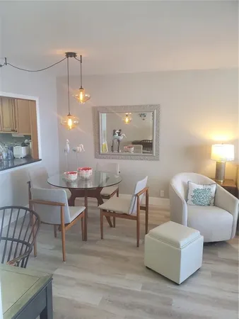 a living room with couches a fireplace and a dining table with wooden floor