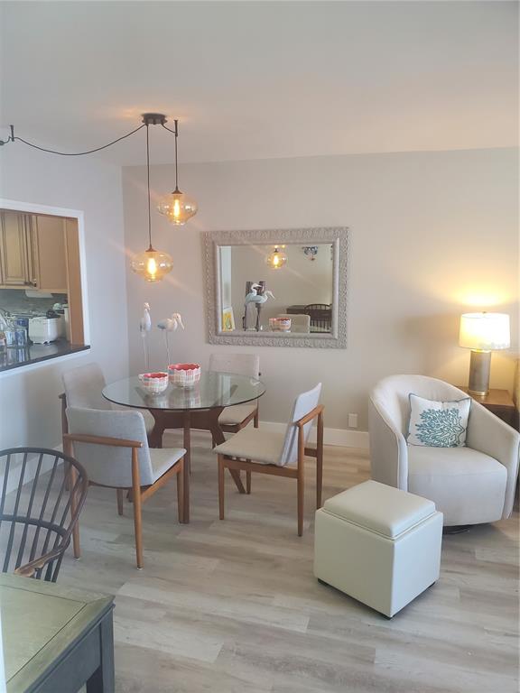 4401 Gulf Of Mexico Drive, Unit 703 Longboat Key, FL 34228 - Photo 3 of 23 a living room with couches a fireplace and a dining table with wooden floor