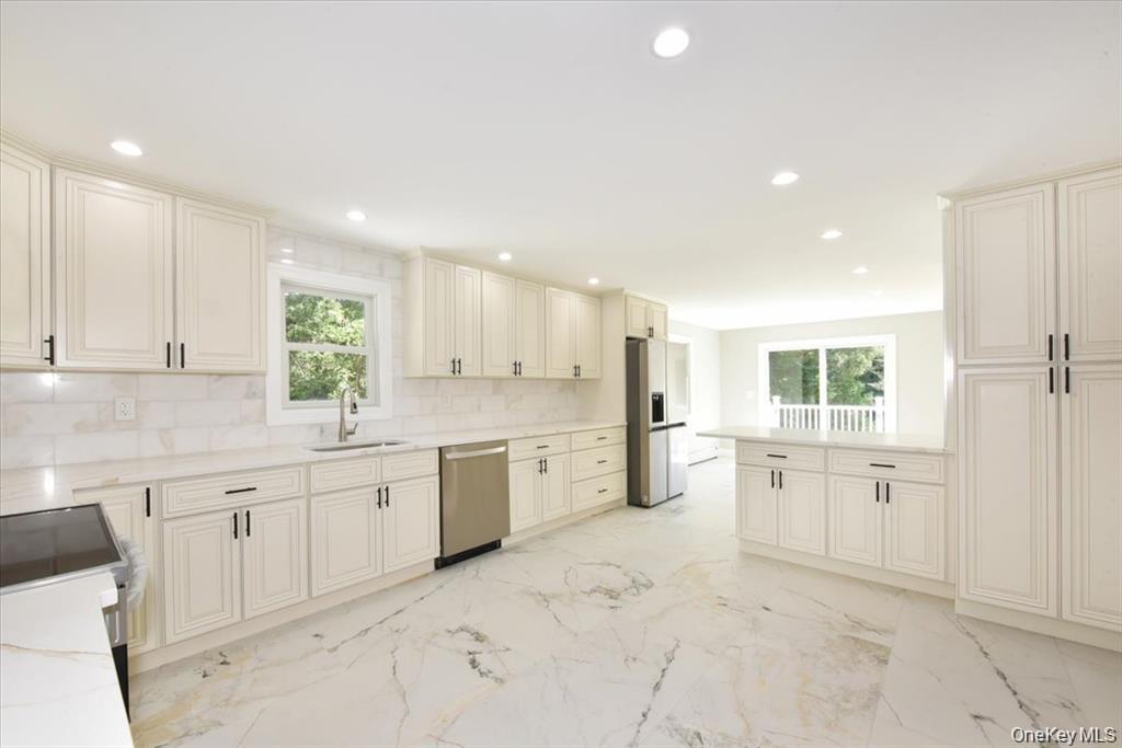 87 Dunlop Road Huntington, NY 11743 - Photo 8 of 31 a large white kitchen with a stove a sink a refrigerator and white cabinets with wooden floor