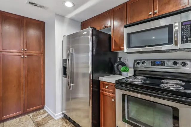 a kitchen with stainless steel appliances granite countertop a refrigerator and a stove top oven