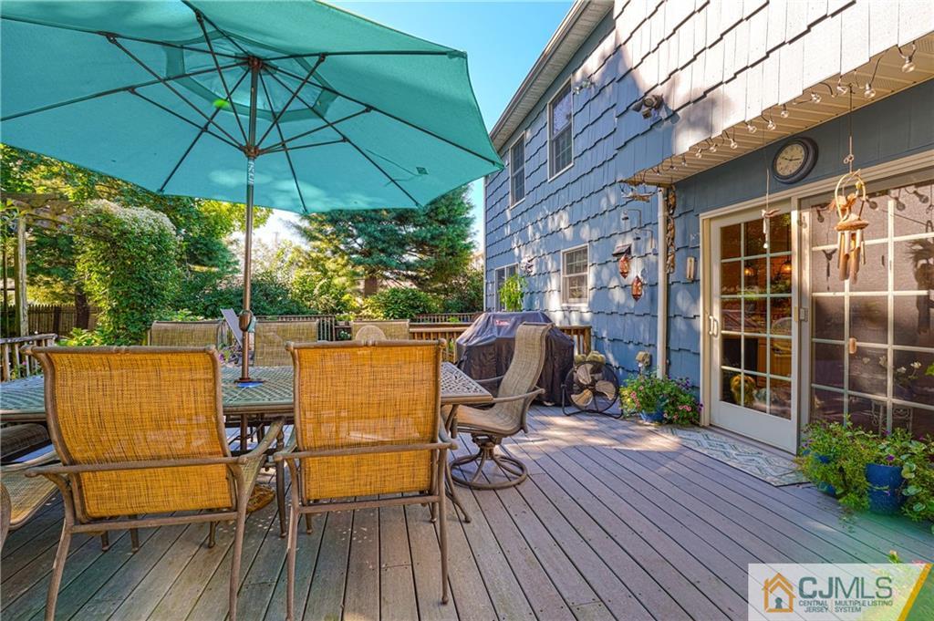 36 Starkin Road Edison, NJ 08837 - Photo 41 of 45 a view of a patio with table and chairs under an umbrella with wooden floor and fence